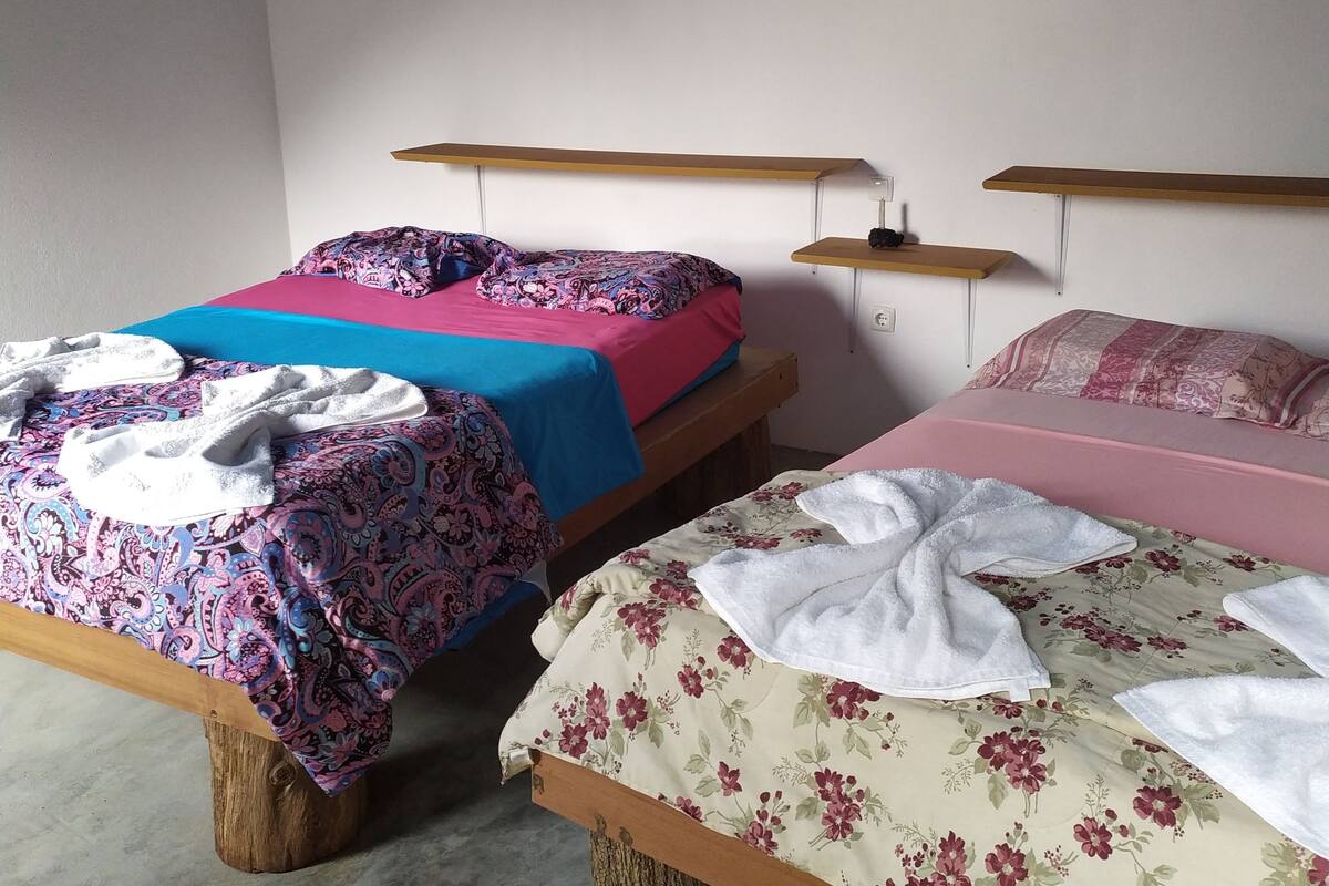 A room with two wooden beds, each with a different patterned bedspread. There are wooden headboards and a ceiling with a blue wave design.