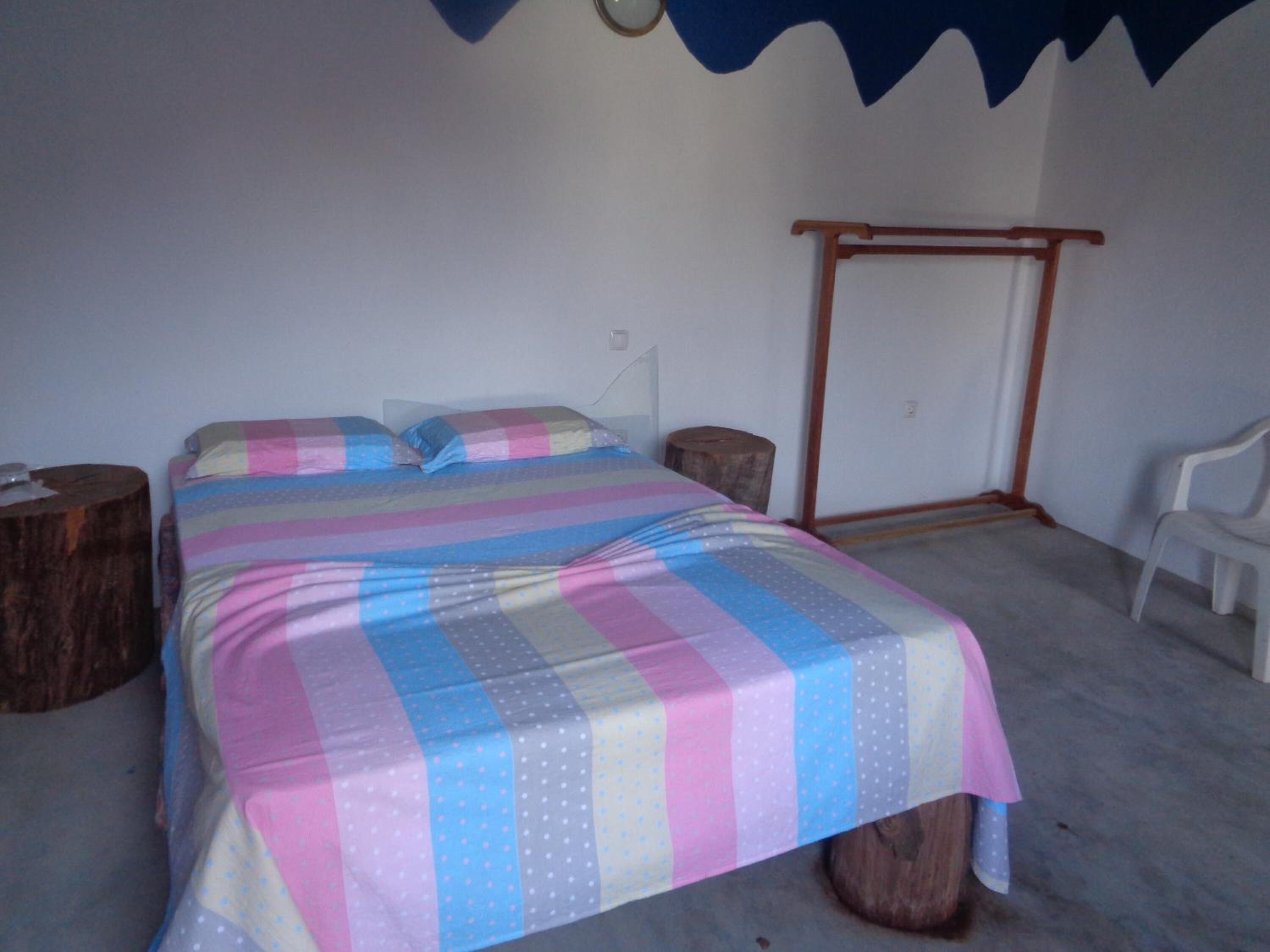 Une chambre à coucher avec un lit, une tête de lit en bois, une table de chevet, une chaise et une horloge murale.