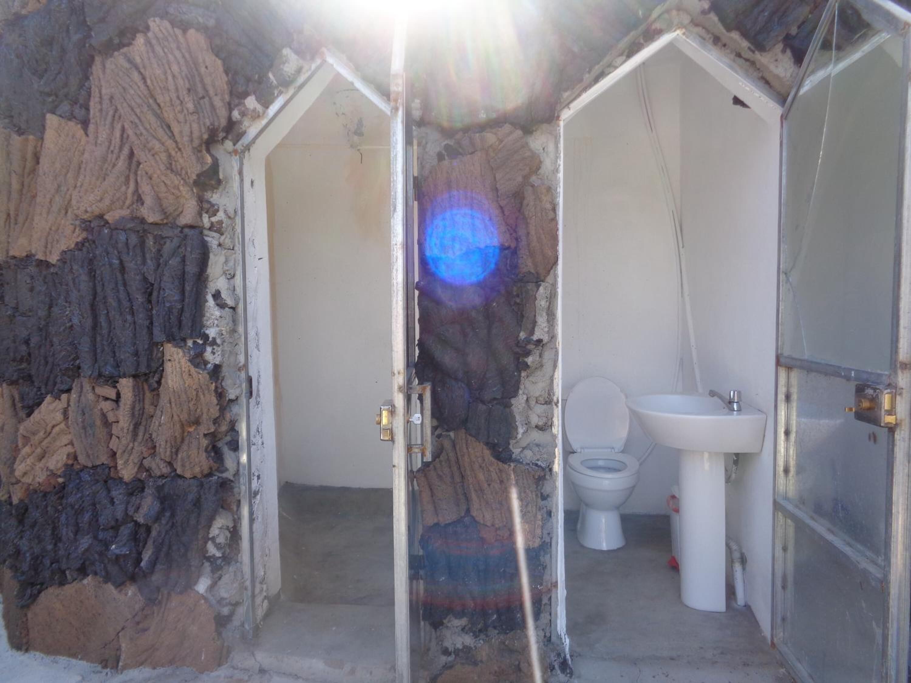 Un baño con pared de piedra, inodoro y lavamanos.