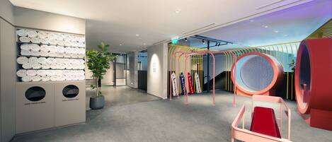 A modern hotel lobby with a towel rack, a plant, a red slide, and a colorful play area.