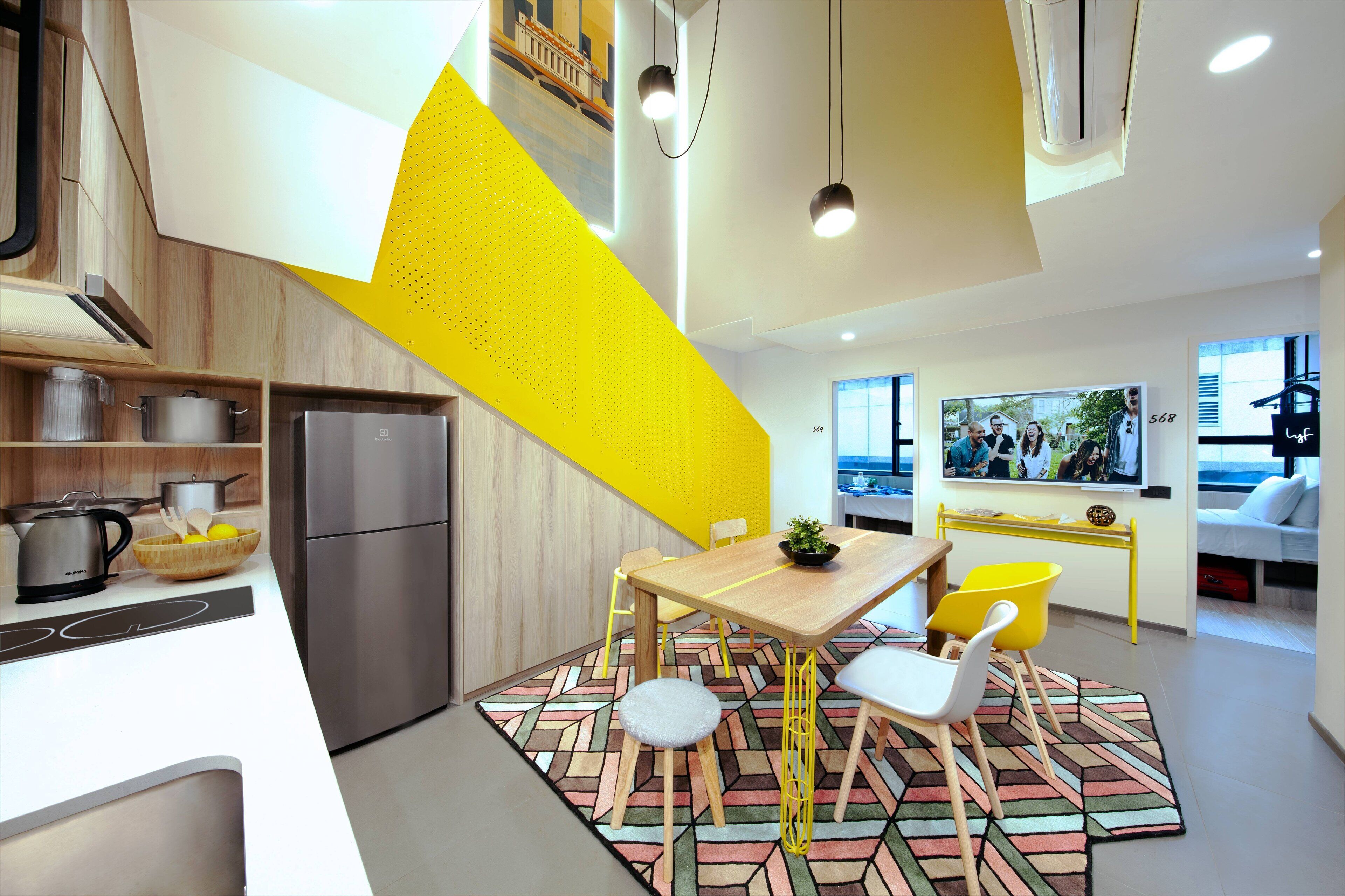 Una cocina moderna con un refrigerador de acero inoxidable, armarios de madera y una pared de acento amarilla.
