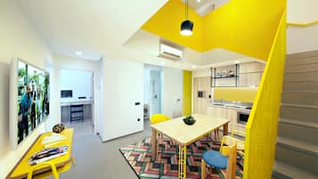 Una sala de estar moderna con una pared de acento amarilla, un comedor con alfombra estampada y una cocina con armarios de madera.