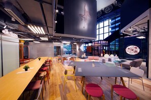 Une salle de conférence moderne, dotée d’une longue table, de nombreuses chaises et d’un espace détente avec des canapés et un coin café.