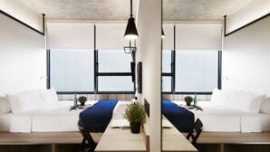 Una camera moderna e minimalista con un tavolo centrale in legno, due divani bianchi e un'ampia finestra che offre luce naturale.