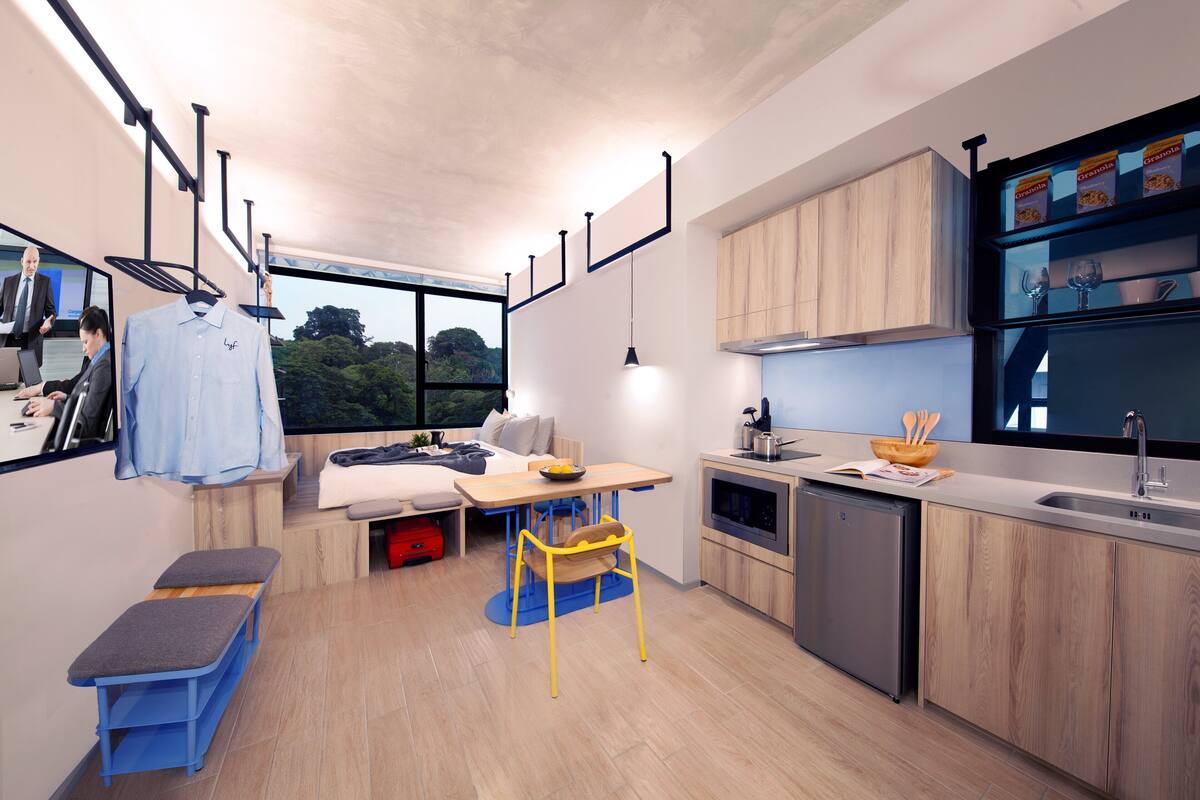 A modern kitchen with wooden cabinets, a built-in oven, and a large window overlooking greenery.