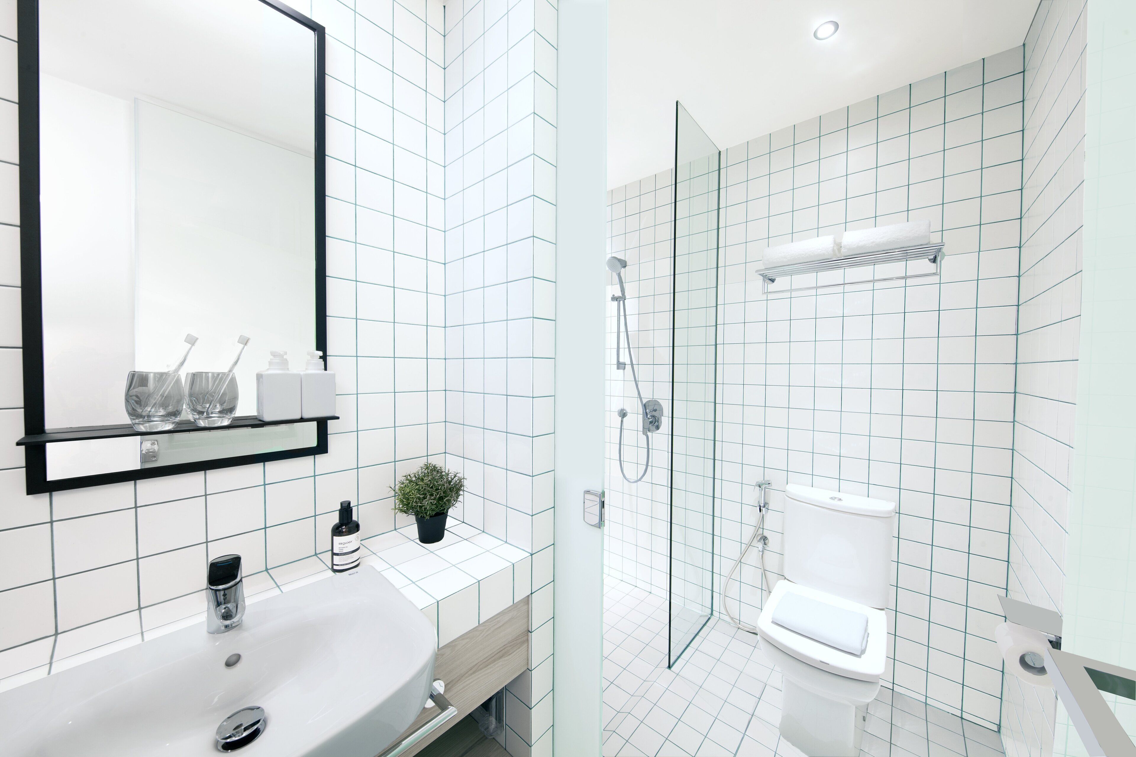 A modern bathroom with a white sink, mirror, and shower.