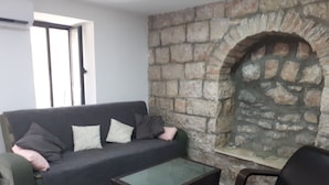 A living room with a stone fireplace, a sofa with cushions, a coffee table, and a chair. - I'm Jerusalem (Jerusalem)