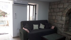 A living room with a dark green sofa, a glass coffee table, and a stone wall. - I'm Jerusalem (Jerusalem)