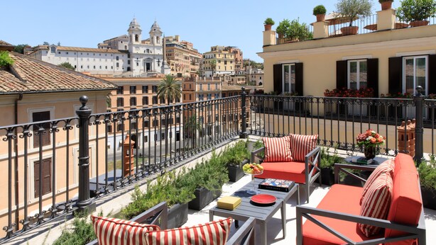 A balcony with outdoor furniture, potted plants, and a view of historic buildings. - Rocco Forte House Piazza di Spagna Roma (Rome)