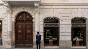 A man standing in front of a building with large wooden doors and two storefronts labeled "TIFFANY & CO." - Rocco Forte House Piazza di Spagna Roma (Rome)