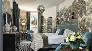 A modern bedroom with a large bed, a blue armchair, a small side table, and a wall mural. - Rocco Forte House Piazza di Spagna Roma (Rome)