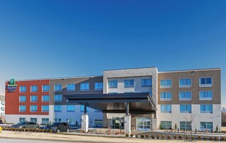A Holiday Inn Express & Suites building with a covered entrance and multiple windows.