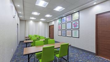 A conference room with tables and chairs, a patterned carpet, and a wall with framed artwork.