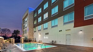 A modern hotel with a swimming pool, outdoor seating, and a well-lit facade. - Holiday Inn Express & Suites Tulsa Northeast - Owasso by IHG (Owasso)