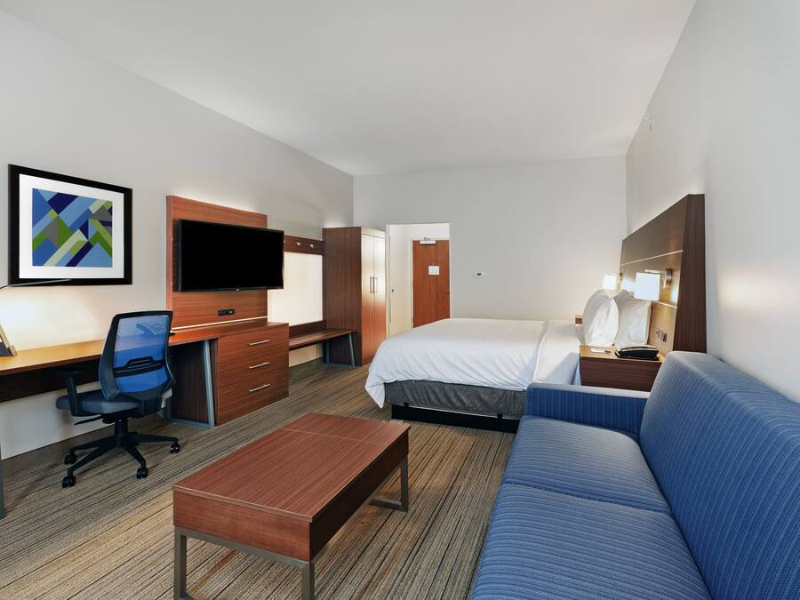 Hotelkamer met een bed, bureau, stoel, bank, televisie en een lijst aan de muur.
