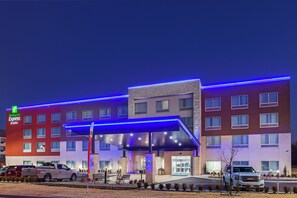 A Holiday Inn Express & Suites hotel with a modern design, featuring a covered entrance and a parking lot with vehicles. - Holiday Inn Express & Suites Tulsa Northeast - Owasso by IHG (Owasso)