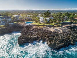 Um resort costeiro com uma linha de costa rochosa, piscina e vários edifícios.