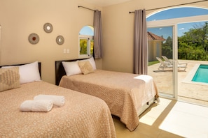 Ein Hotelzimmer mit zwei Betten, einem großen Fenster und Blick auf Pool und Außenbereich.
