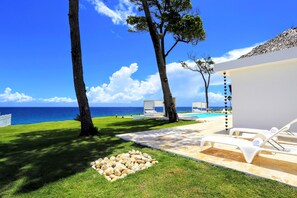 A beachside resort with a pool, lounge chairs, and a view of the ocean.