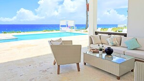 Una habitación con vista al océano, una piscina y mobiliario exterior.