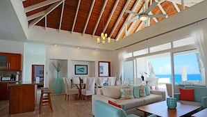 A spacious living area with a high ceiling, a dining set, and a view of the ocean. - Ocean Front Villa Deluxe 4 Bedroom (Sosúa)