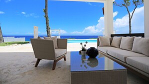 A beachside room with a view of the ocean, featuring a sofa, chairs, and a coffee table. - Ocean Front Villa Deluxe 4 Bedroom (Sosúa)