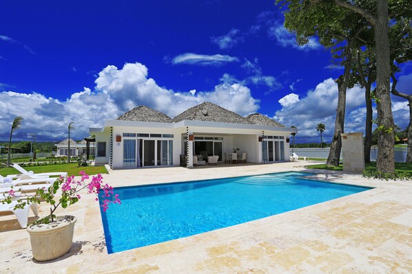 Una casa moderna con piscina, ventanas amplias y un patio.
