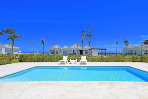 Relax by the resort pool surrounded by lush greenery and palm trees.
