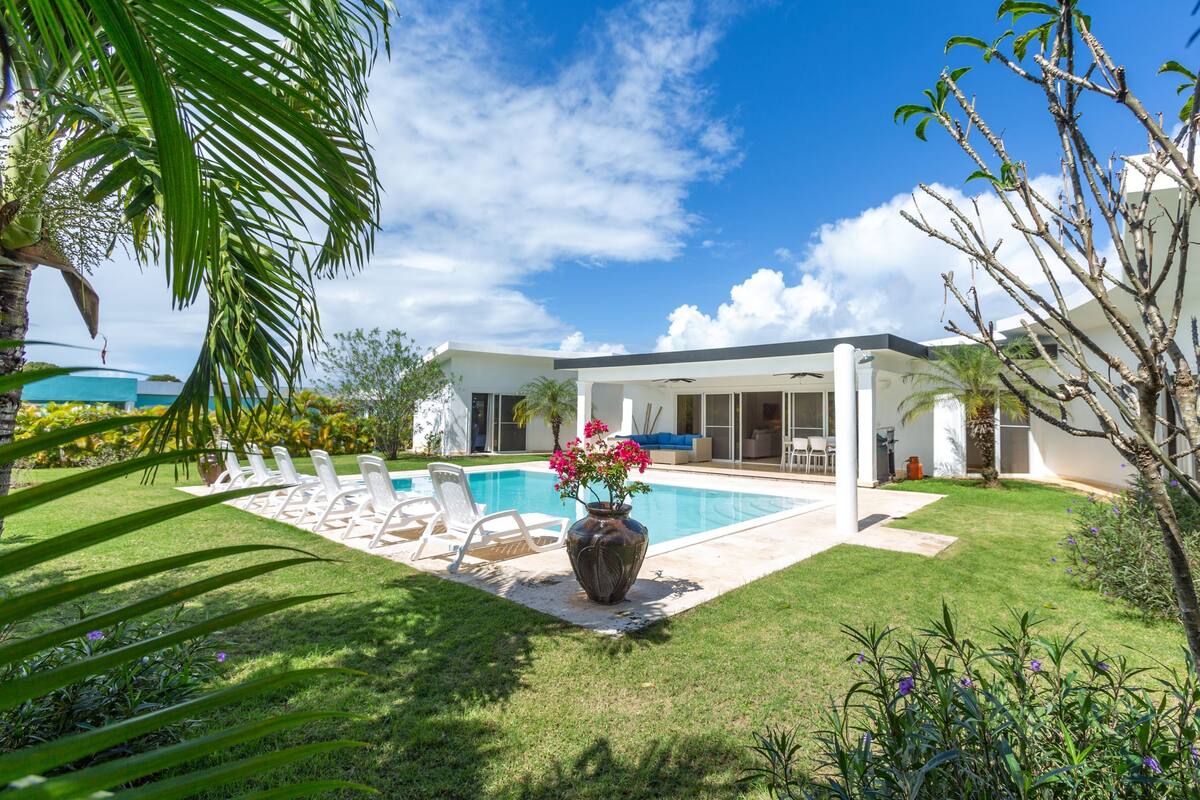 Une maison moderne dotée d’une piscine, d’un patio couvert et d’une pelouse bien entretenue.
