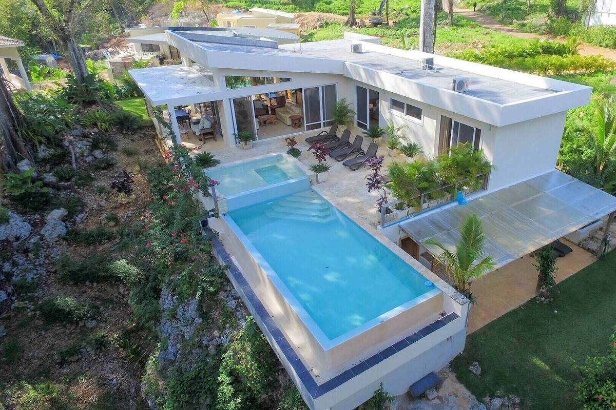 Une maison moderne dotée d’une piscine, d’un espace salon extérieur et d’une végétation luxuriante.