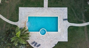An aerial view of a rectangular swimming pool with a circular hot tub, surrounded by a paved deck and a palm tree. - Sosua Ocean Village Properties by Calisto Stays (Sosúa)