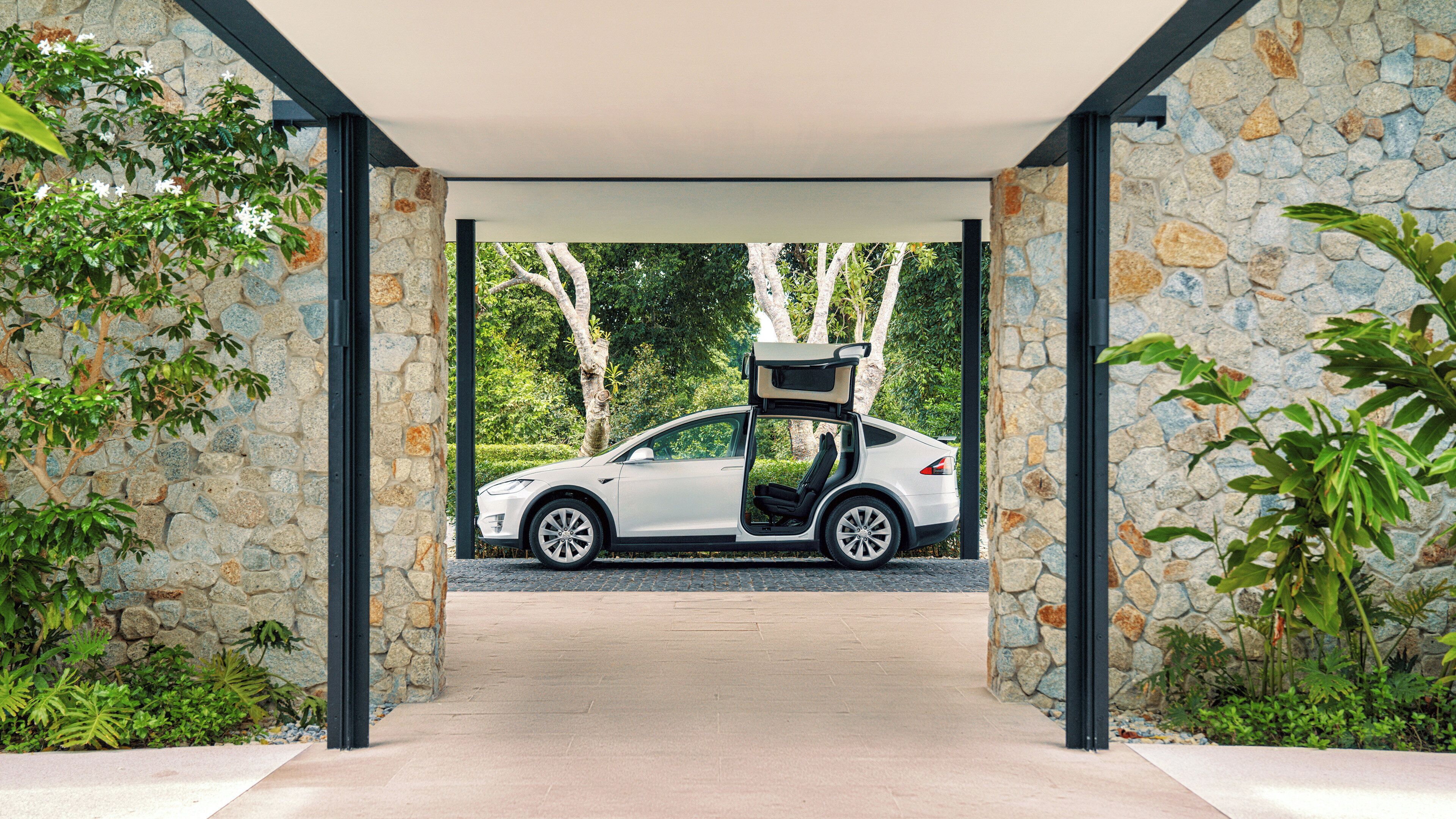 A modern car parked under a stone archway with a covered walkway.