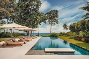 Relax by the pool surrounded by lush greenery and ocean views.