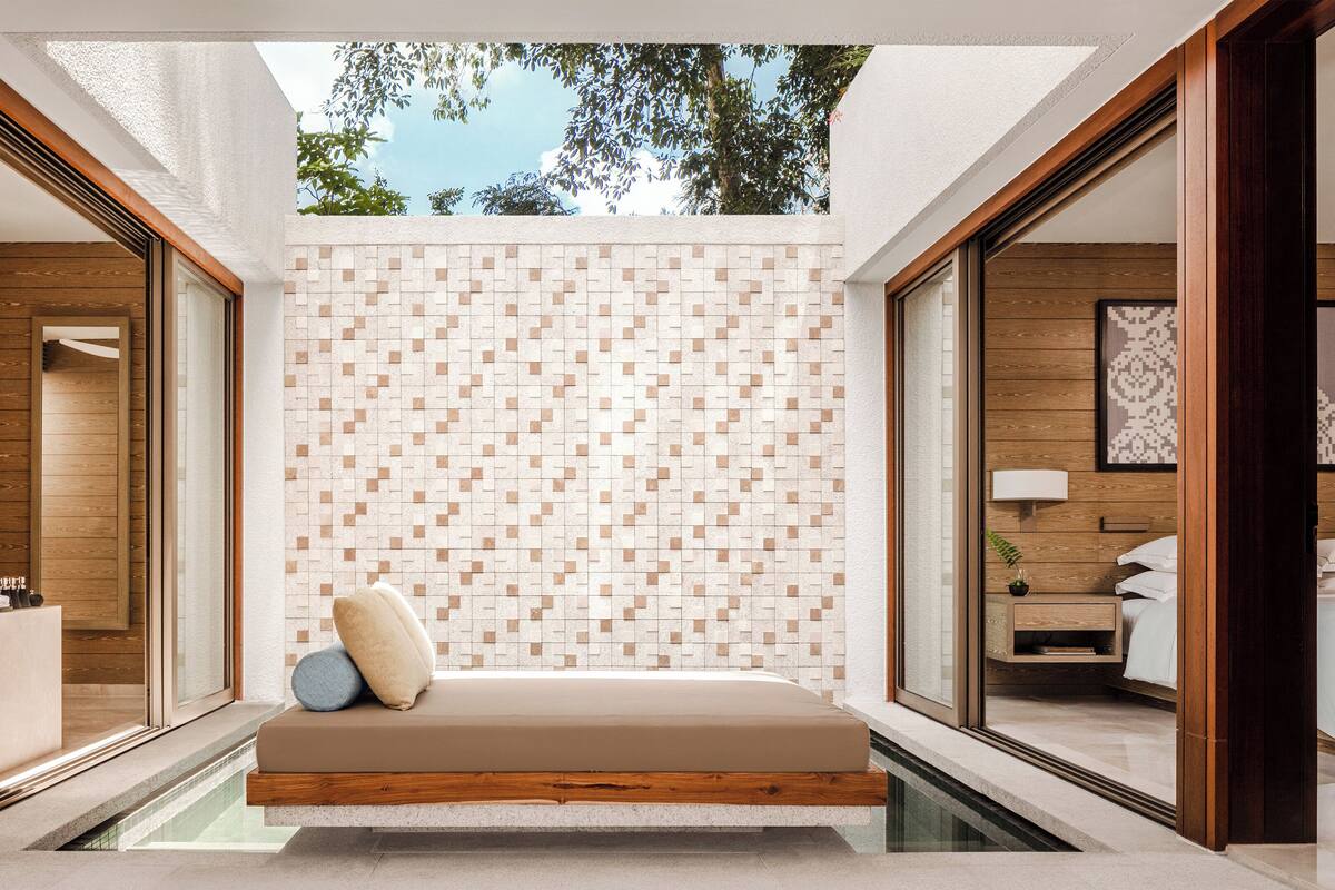 A modern bedroom with a built-in bench, a tiled wall, and a view of the outdoors.