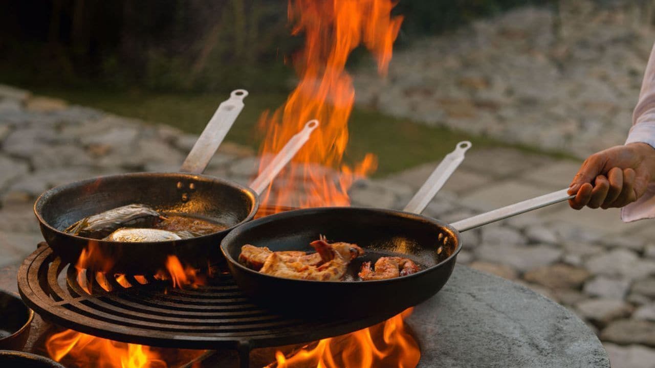 Una parrilla con dos sartenes sobre llamas abiertas.