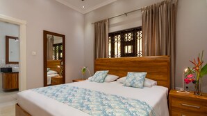A bedroom with a large bed, wooden headboard, and a nightstand with a lamp.