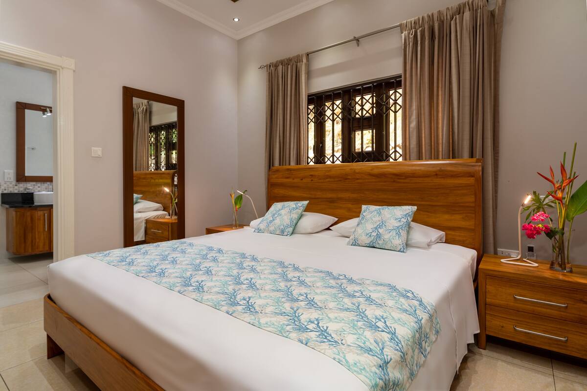 Un dormitorio con una cama grande, cabecera de madera y una mesita de noche con lámpara.