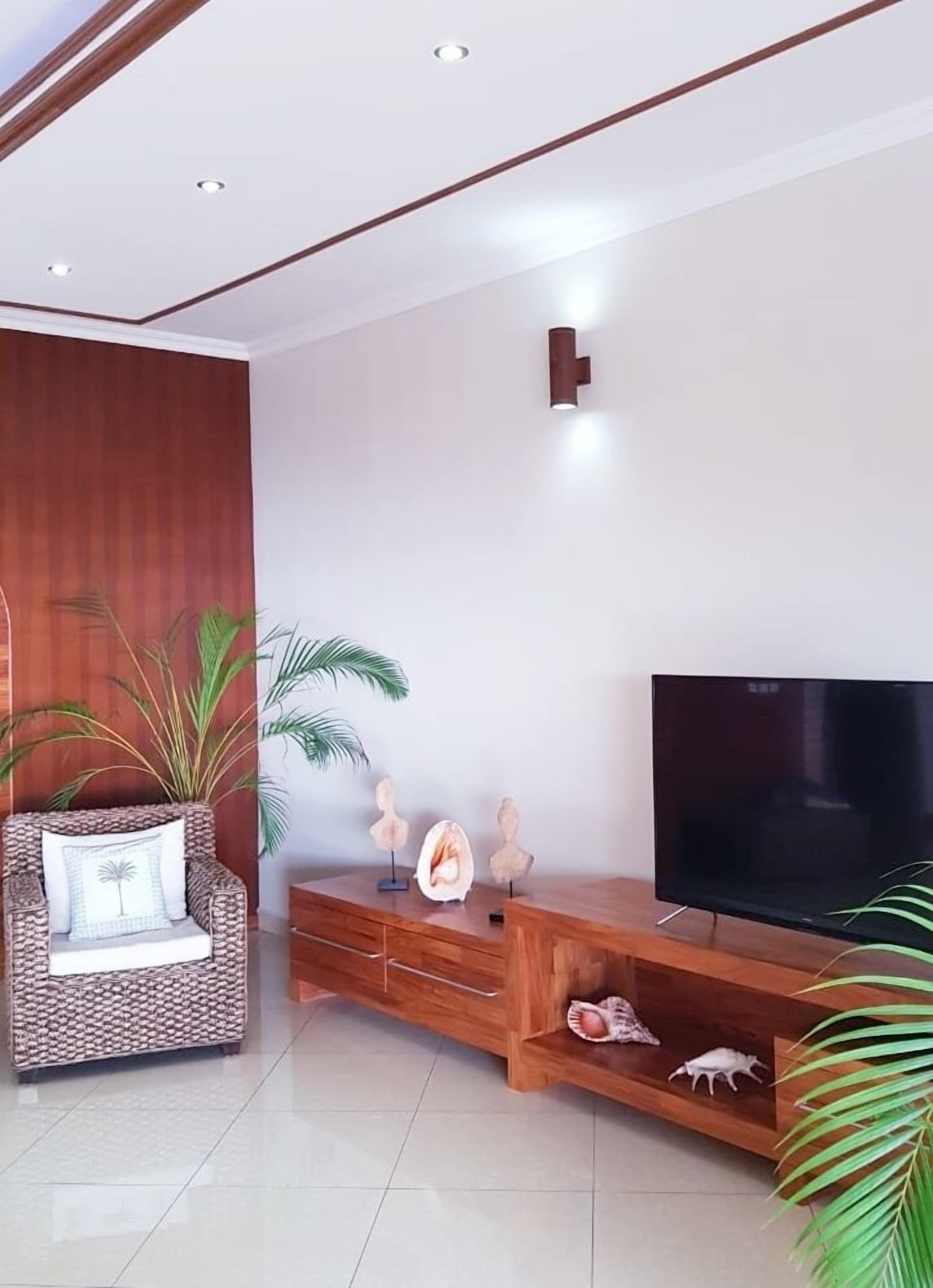 A modern living room with a wooden entertainment unit, a flat-screen TV, and a comfortable sofa.