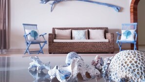 A living room with a brown sofa, two blue chairs, a wall-mounted sculpture, and a large arched doorway.