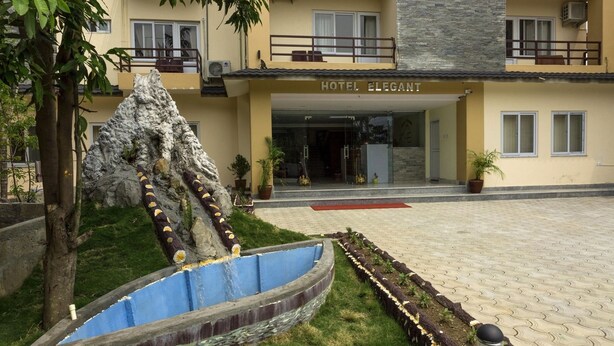 Hotel con jardín ajardinado que presenta una formación rocosa y un elemento acuático azul.