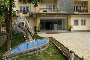 A hotel with a landscaped garden featuring a rock formation and a blue water feature. - Hotel Elegant (Pokhara)