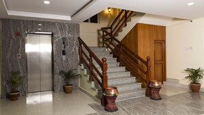 Un vestíbulo moderno con suelo de mármol, una escalera de madera y una puerta.
