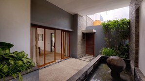 Een modern gebouw met een glazen entree, een kleine waterpartij en potplanten.