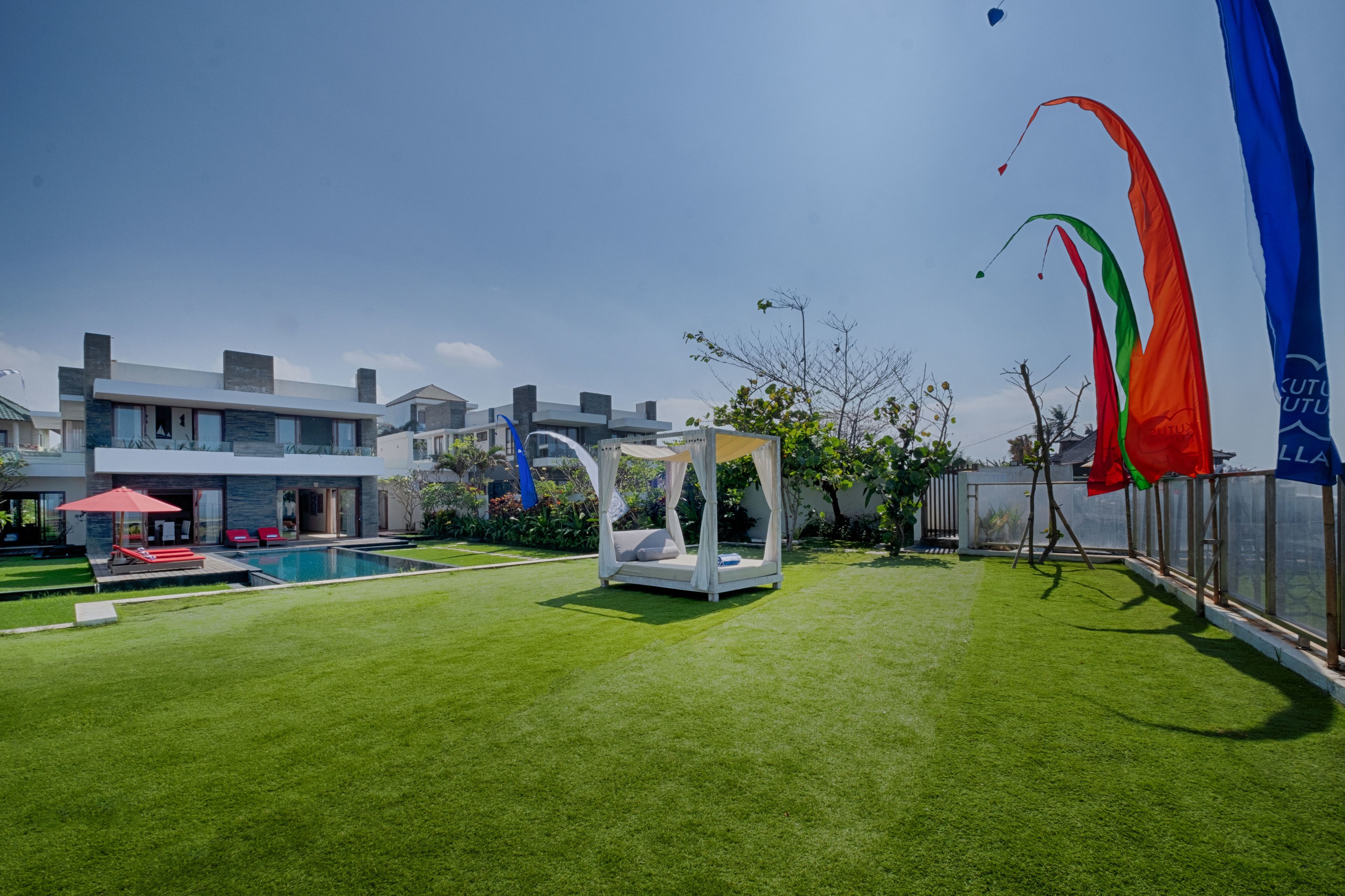 Un espacio exterior moderno con piscina, una estructura tipo dosel blanca y banderas.