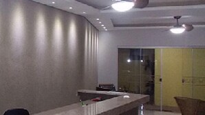 Un'area reception moderna con un bancone in cemento, ventilatori a soffitto e illuminazione a incasso.