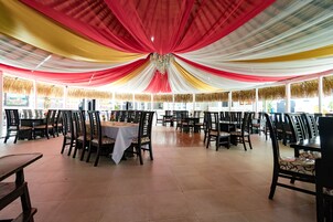 Un amplio comedor interior con mesas y sillas, suelo de baldosas y techo decorado con tela de colores.