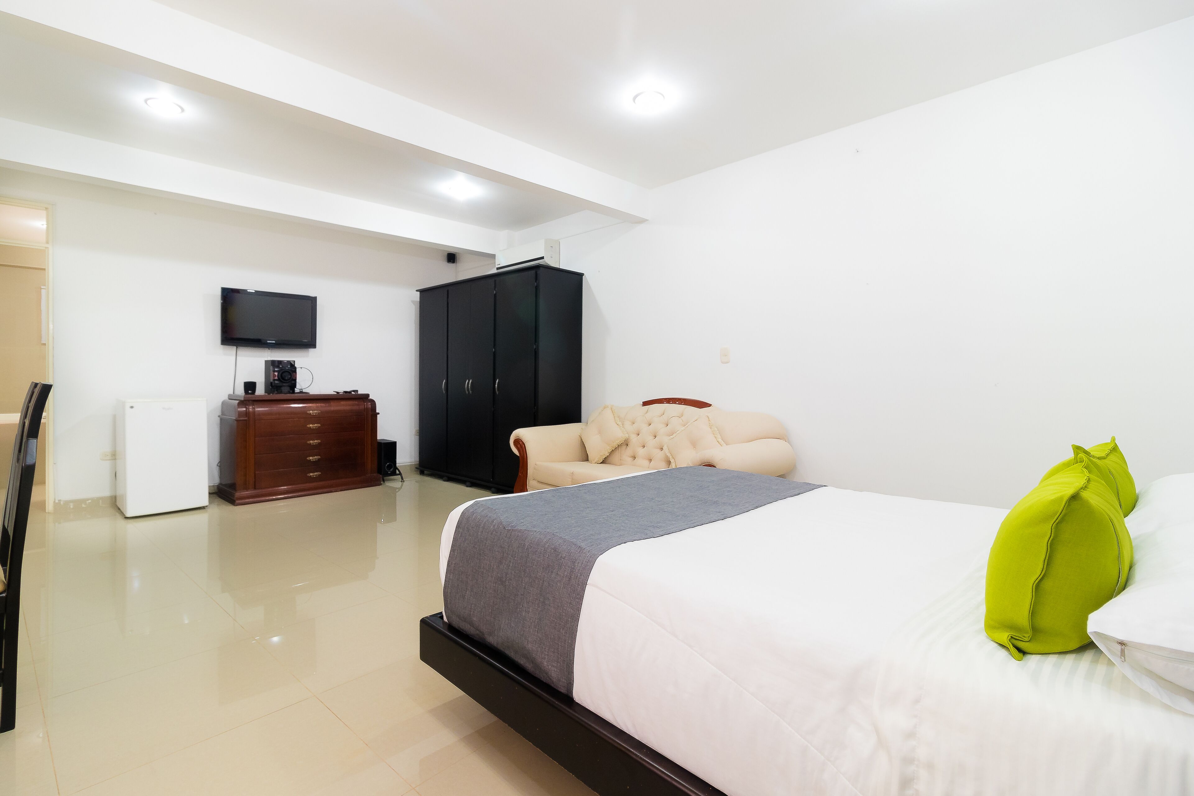 Un dormitorio con cama, televisión, armario y escritorio con computadora.