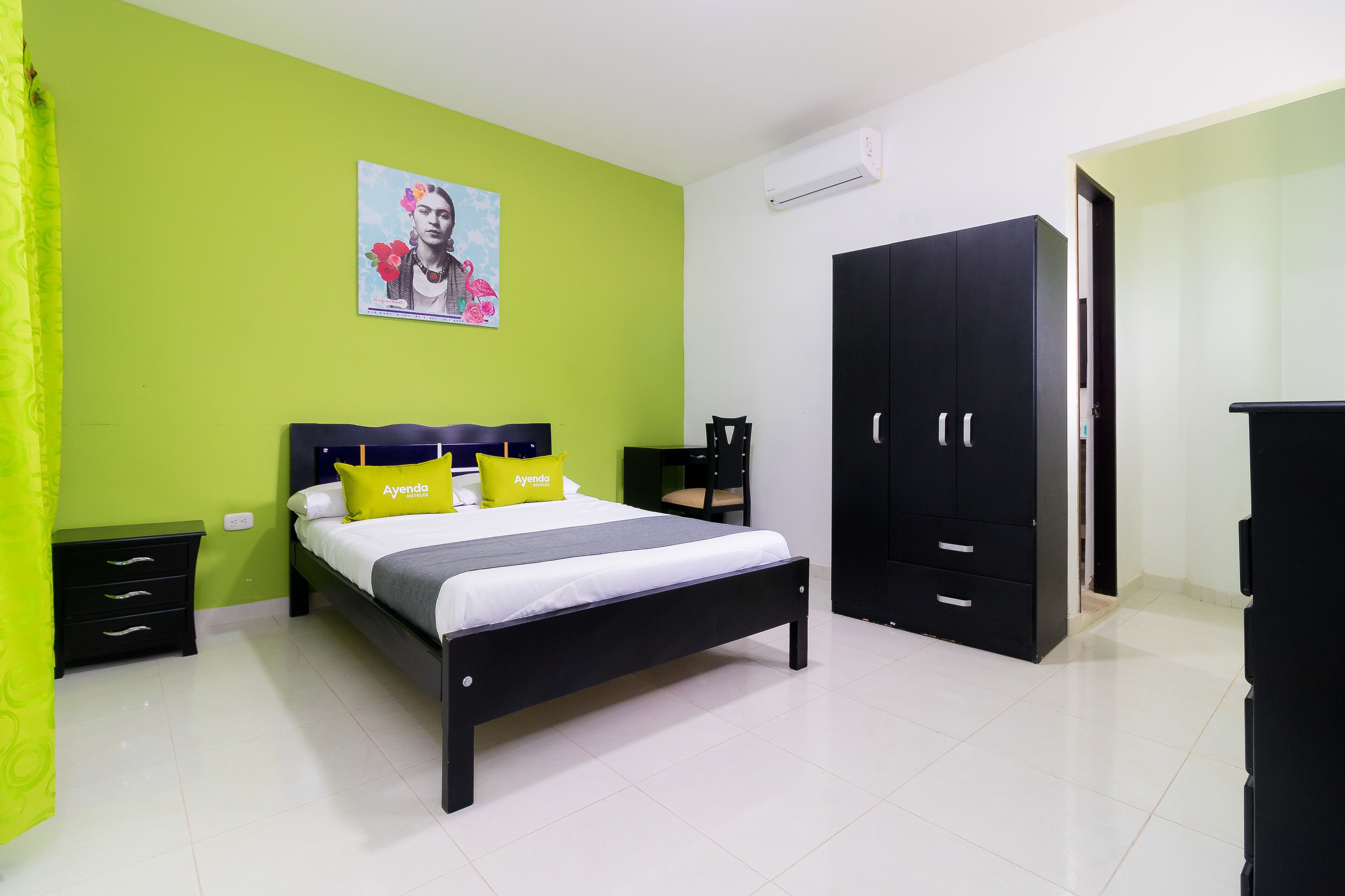 Une chambre à coucher comprenant un lit, une armoire, une table de chevet et un climatiseur fixé au mur.