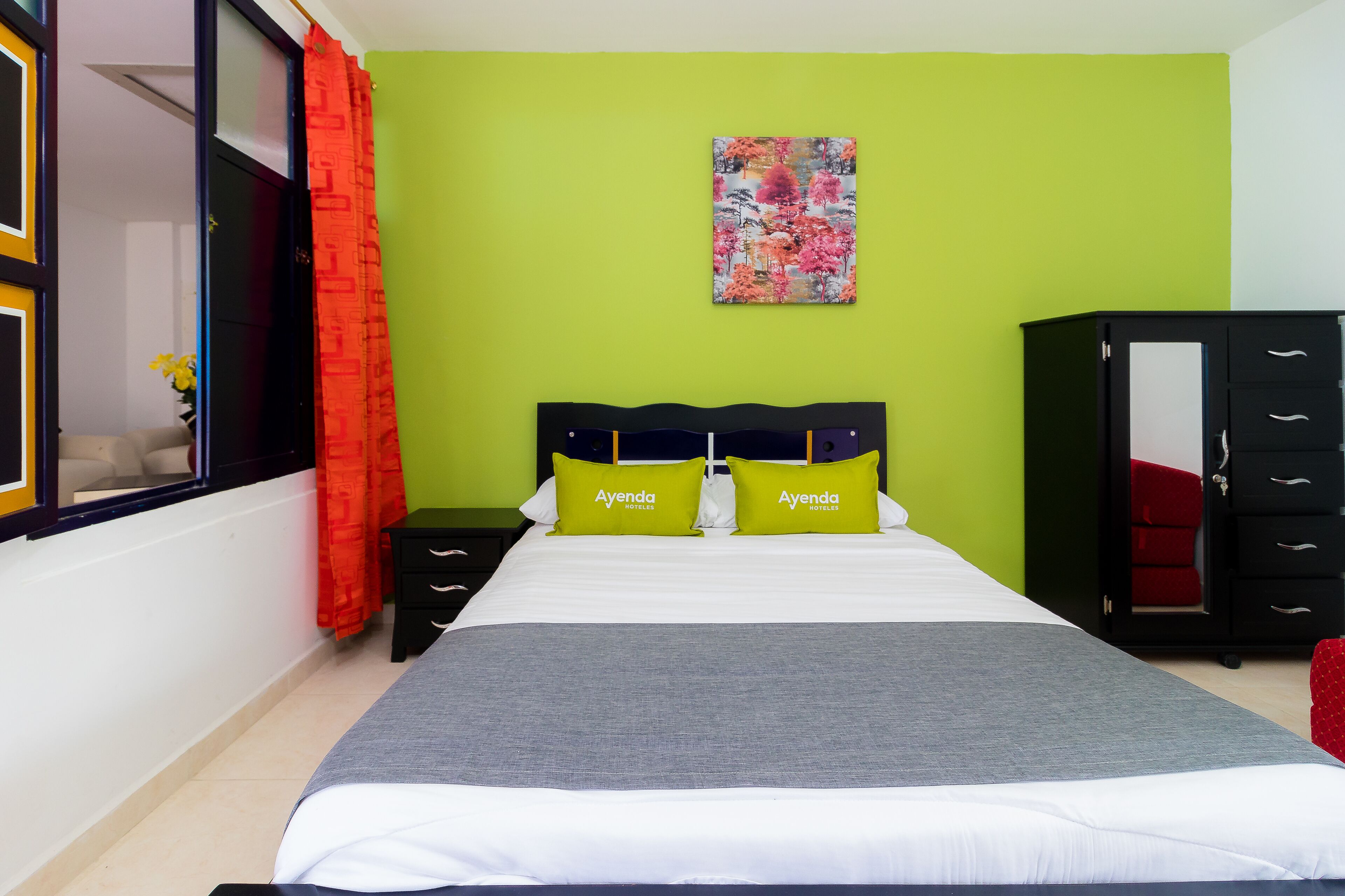 Ein Hotelzimmer mit Bett, Nachttisch, Kommode und einem Bild an der Wand.