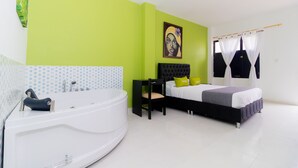 Une chambre moderne avec un grand lit, une tête de lit noire et un mur d’accent vert.